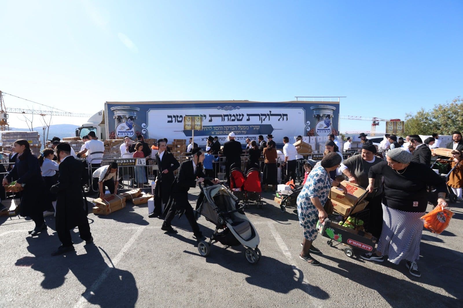 Families with strollers and carts collecting packages at the Yom Tov distribution site