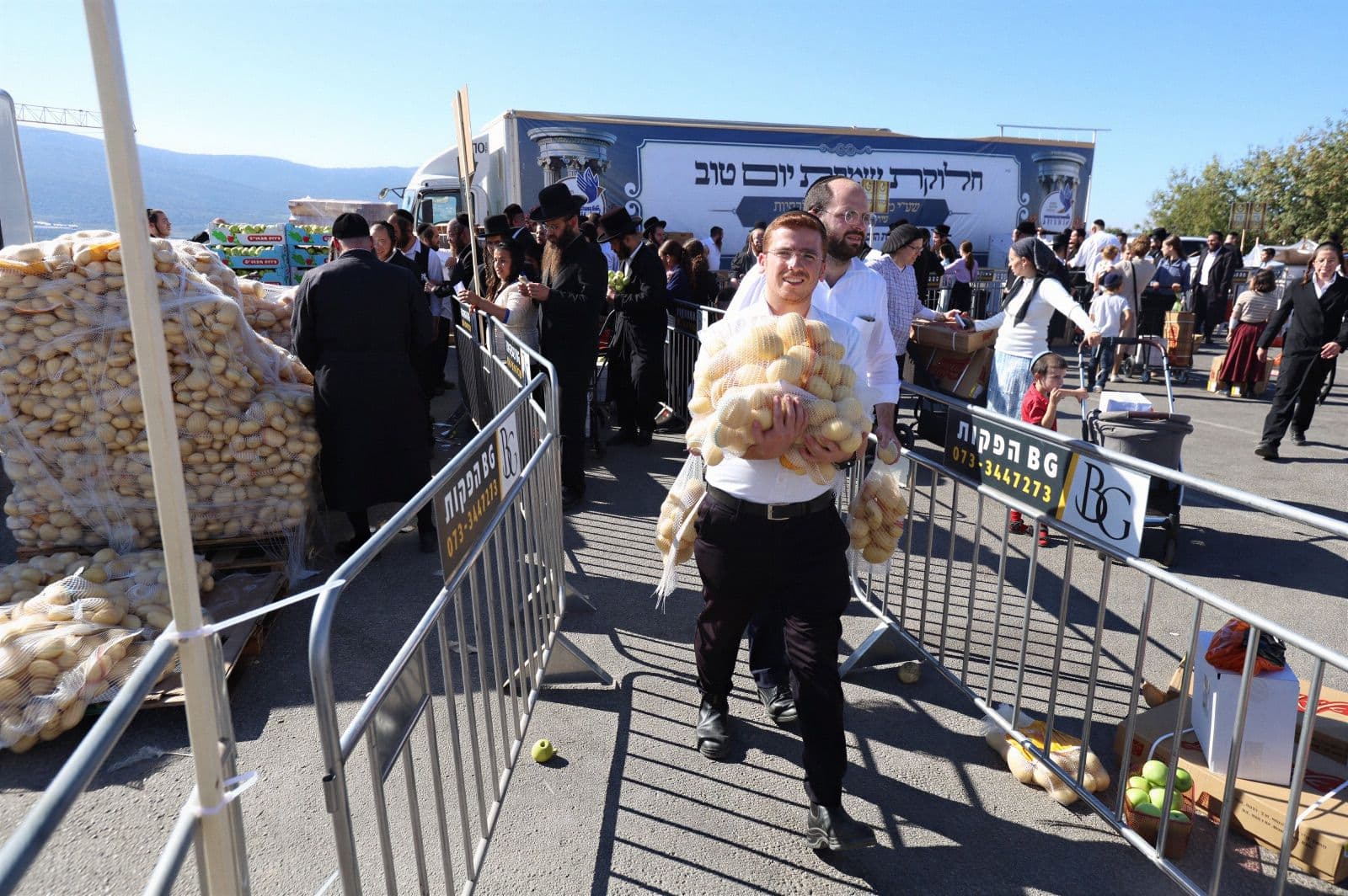 A volunteer carrying sacks of potatoes past the distribution truck before Yom Tov